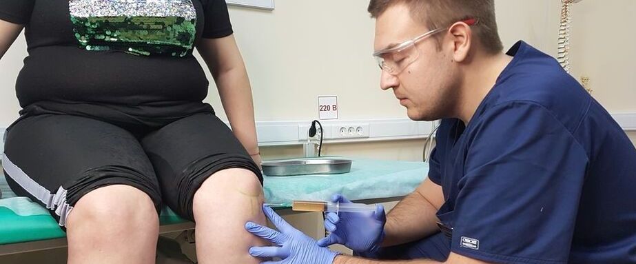 Ortopedický lekár robí intraartikulárnu injekciu do kolenného kĺbu na artrózu